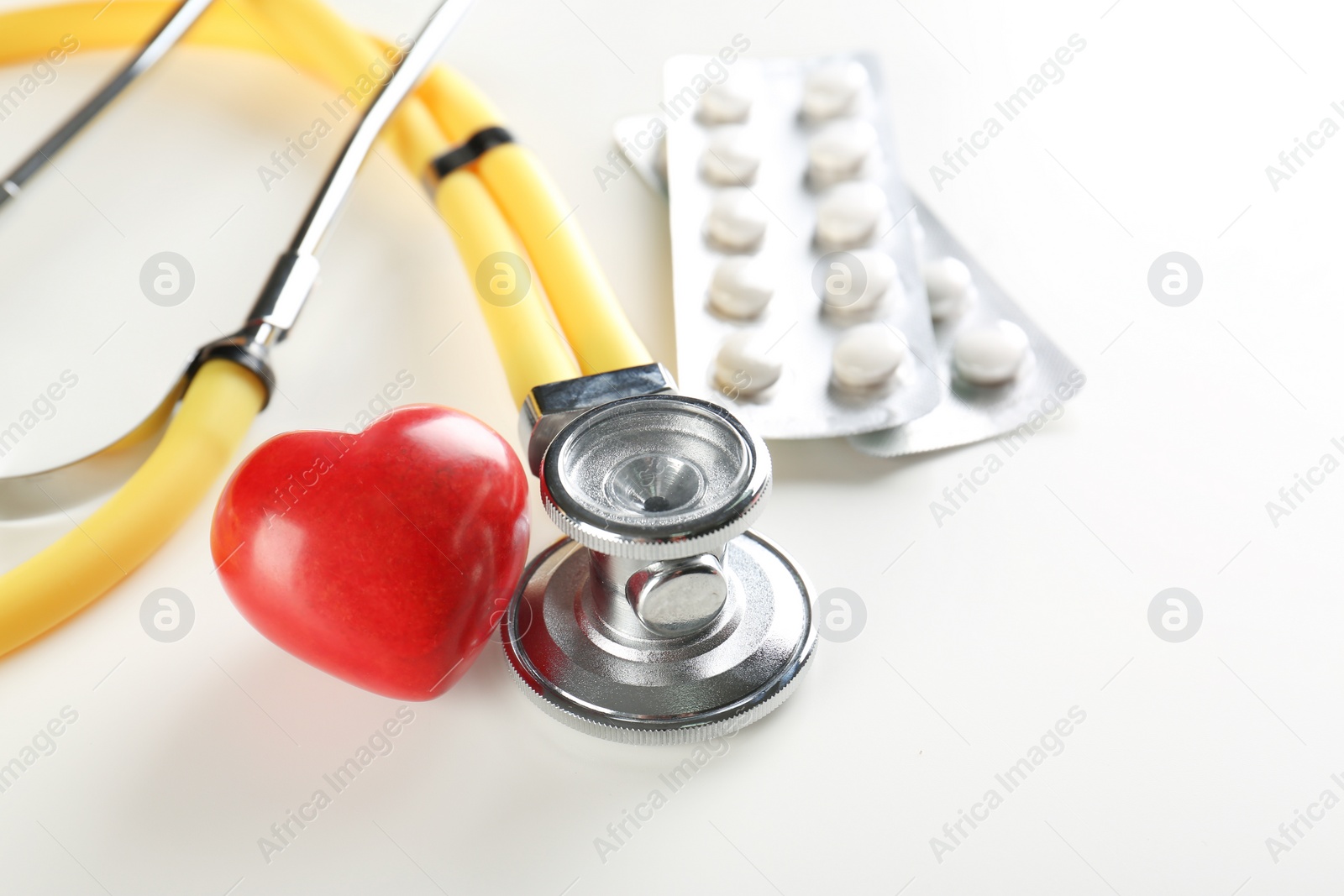 Photo of Stethoscope, pills and small red heart on table. Heart attack concept