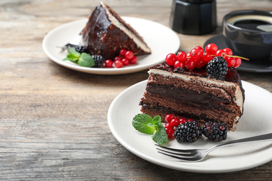 Photo of Tasty chocolate cake with berries on wooden table. Space for text