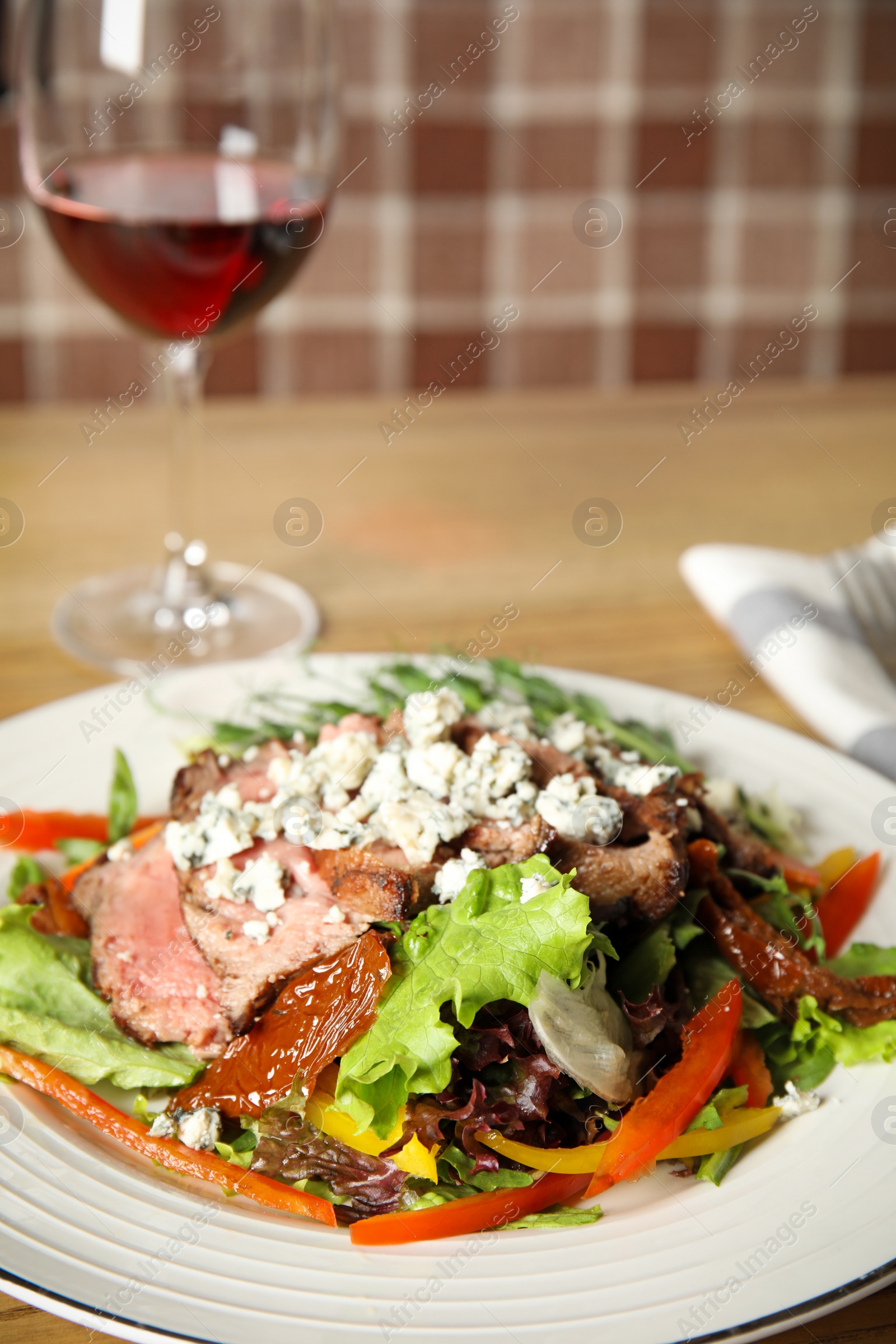 Photo of Delicious salad with roasted meat and vegetables served on wooden table, closeup. Space for text