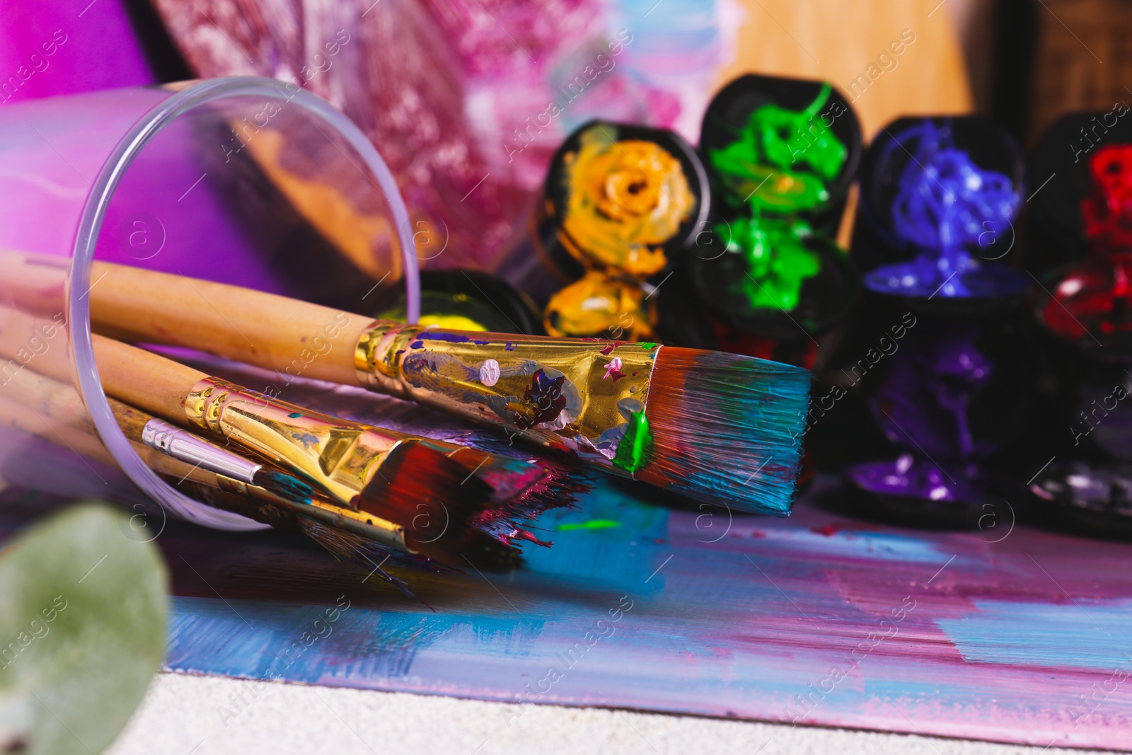 Photo of Brushes with colorful paints and canvas, closeup