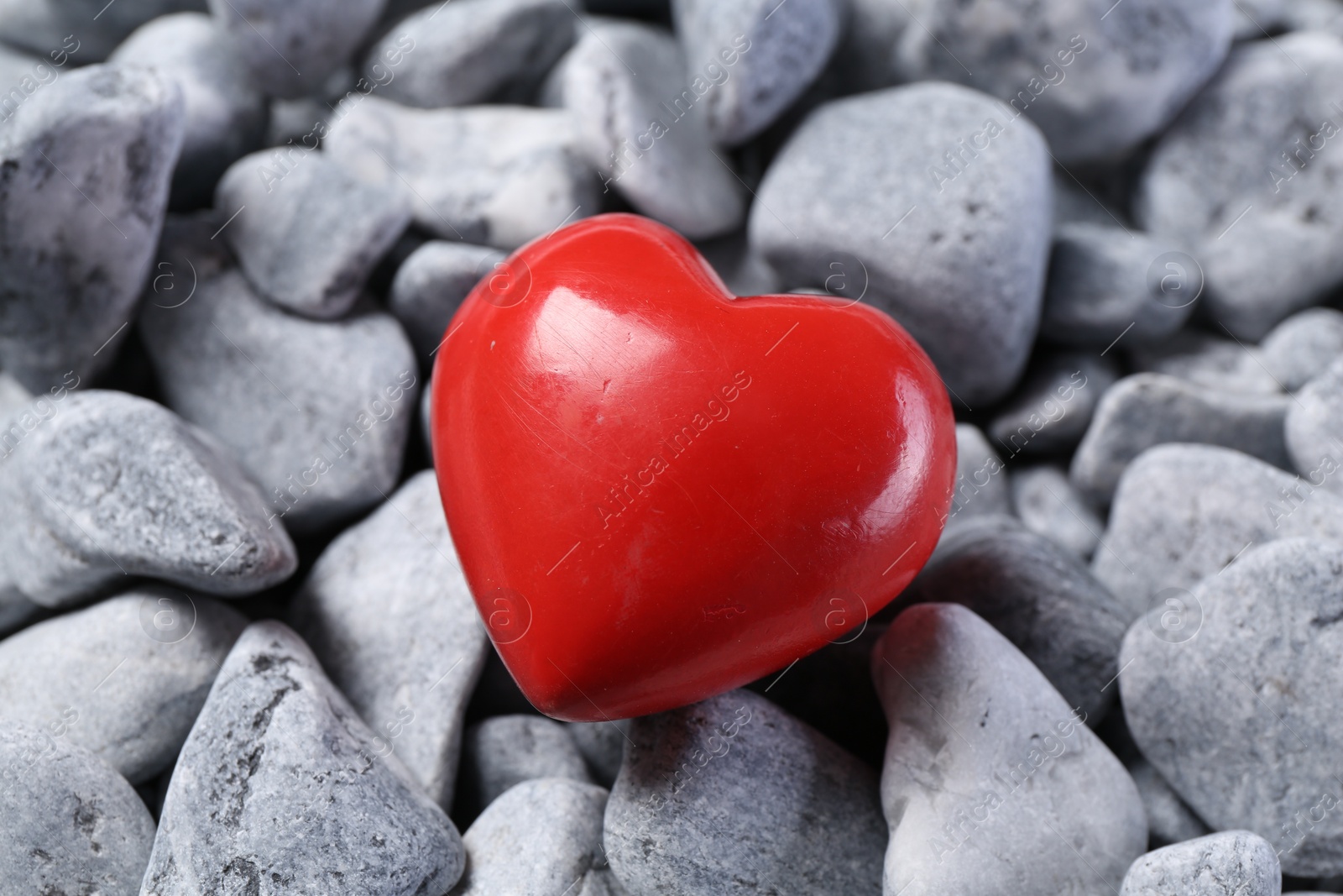 Photo of One red decorative heart on grey stones, closeup