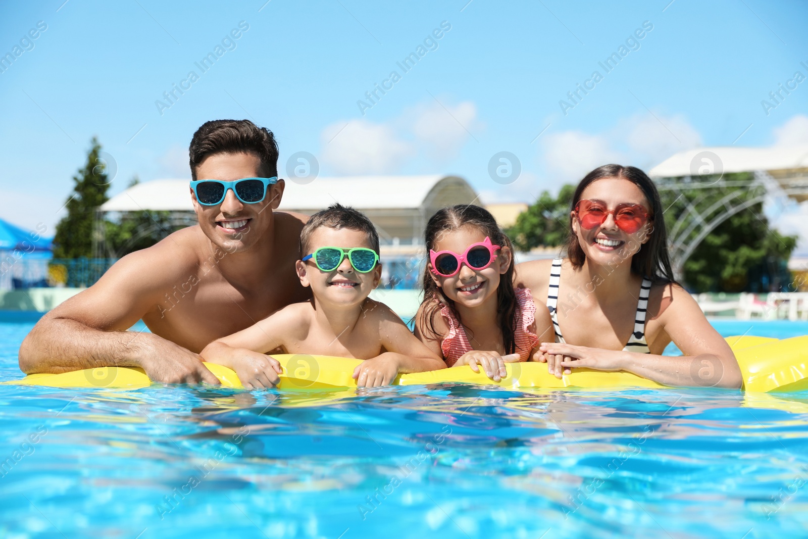 Photo of Happy family with inflatable mattress in swimming pool. Summer vacation