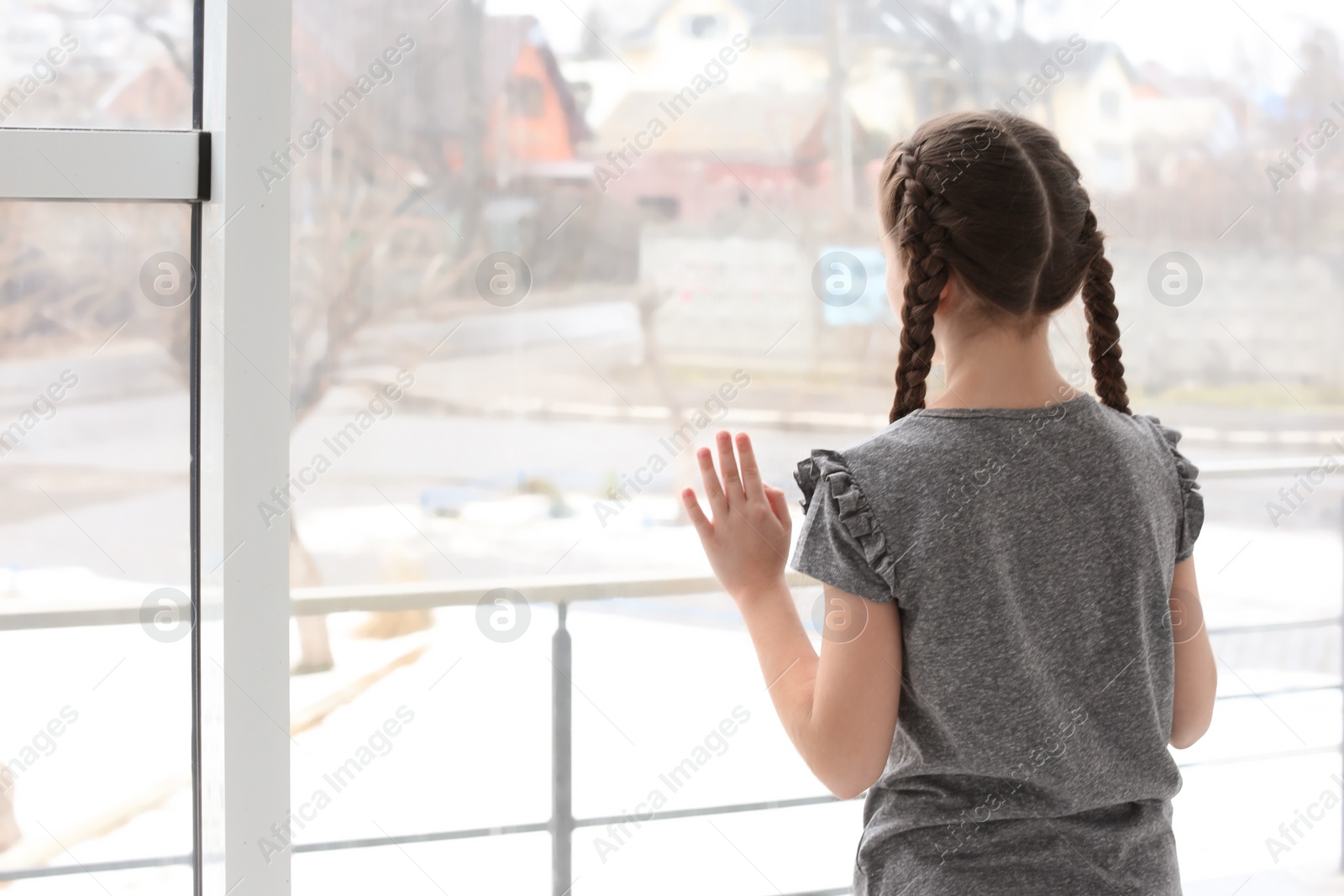 Photo of Lonely little girl near window indoors. Child autism