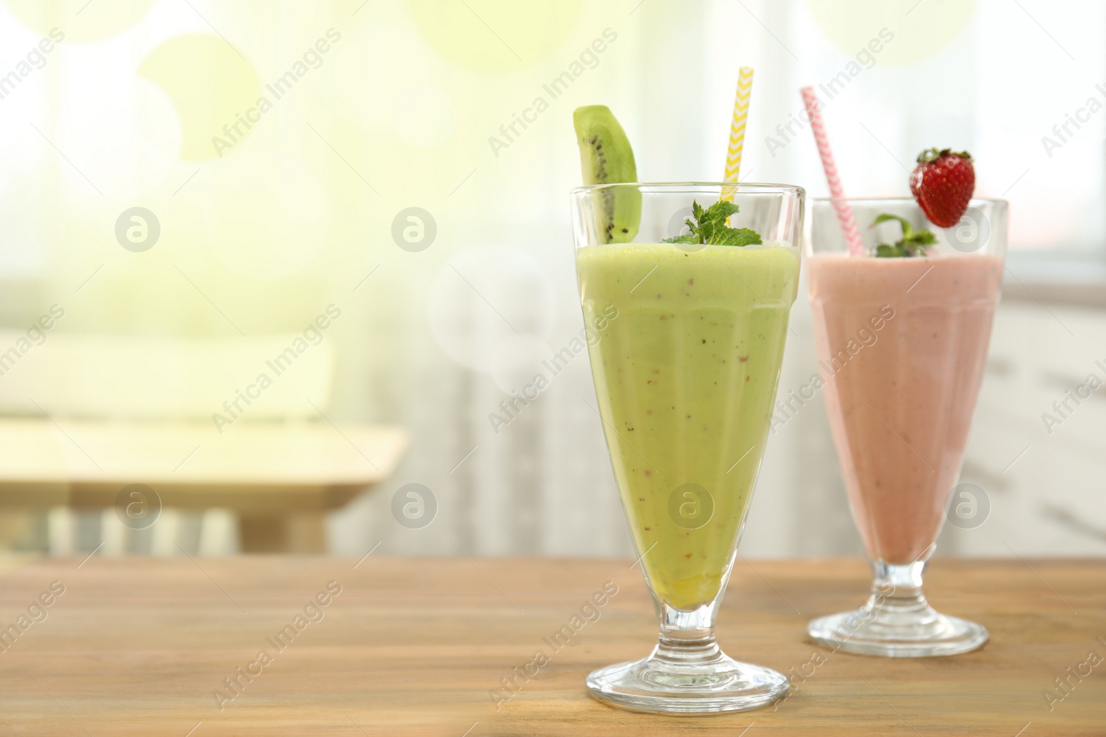 Photo of Tasty fresh milk shakes with berries on wooden table indoors. Space for text