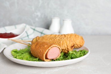 Photo of Delicious corn dogs with lettuce on light table