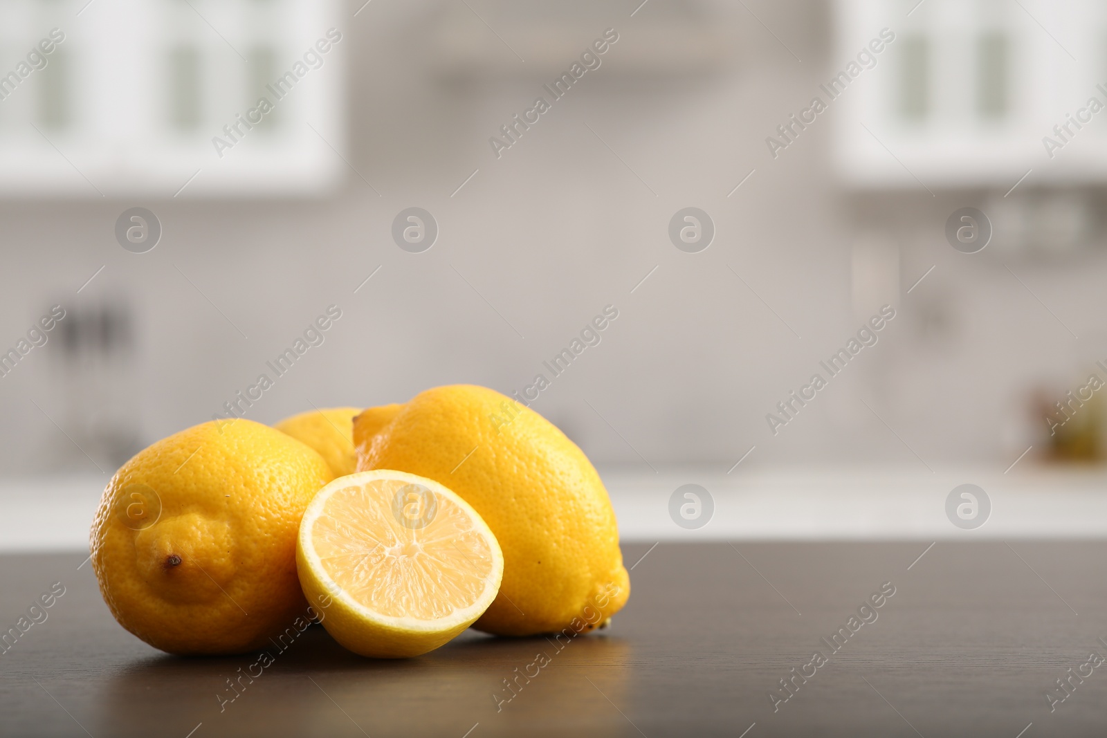 Photo of Whole and cut lemons on wooden counter in kitchen, space for text