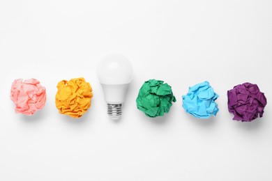 Photo of Creative flat lay composition with lightbulb and colorful paper balls on white background. Idea concept