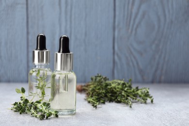 Photo of Thyme essential oil on light grey table, space for text