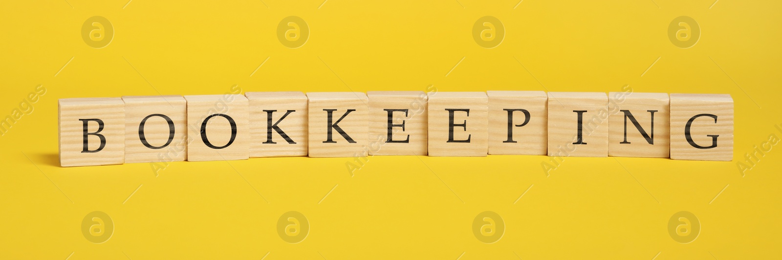 Photo of Word Bookkeeping made with wooden cubes on yellow background