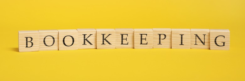 Word Bookkeeping made with wooden cubes on yellow background