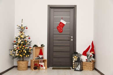 Christmas stocking hanging on wooden door and festive decoration indoors
