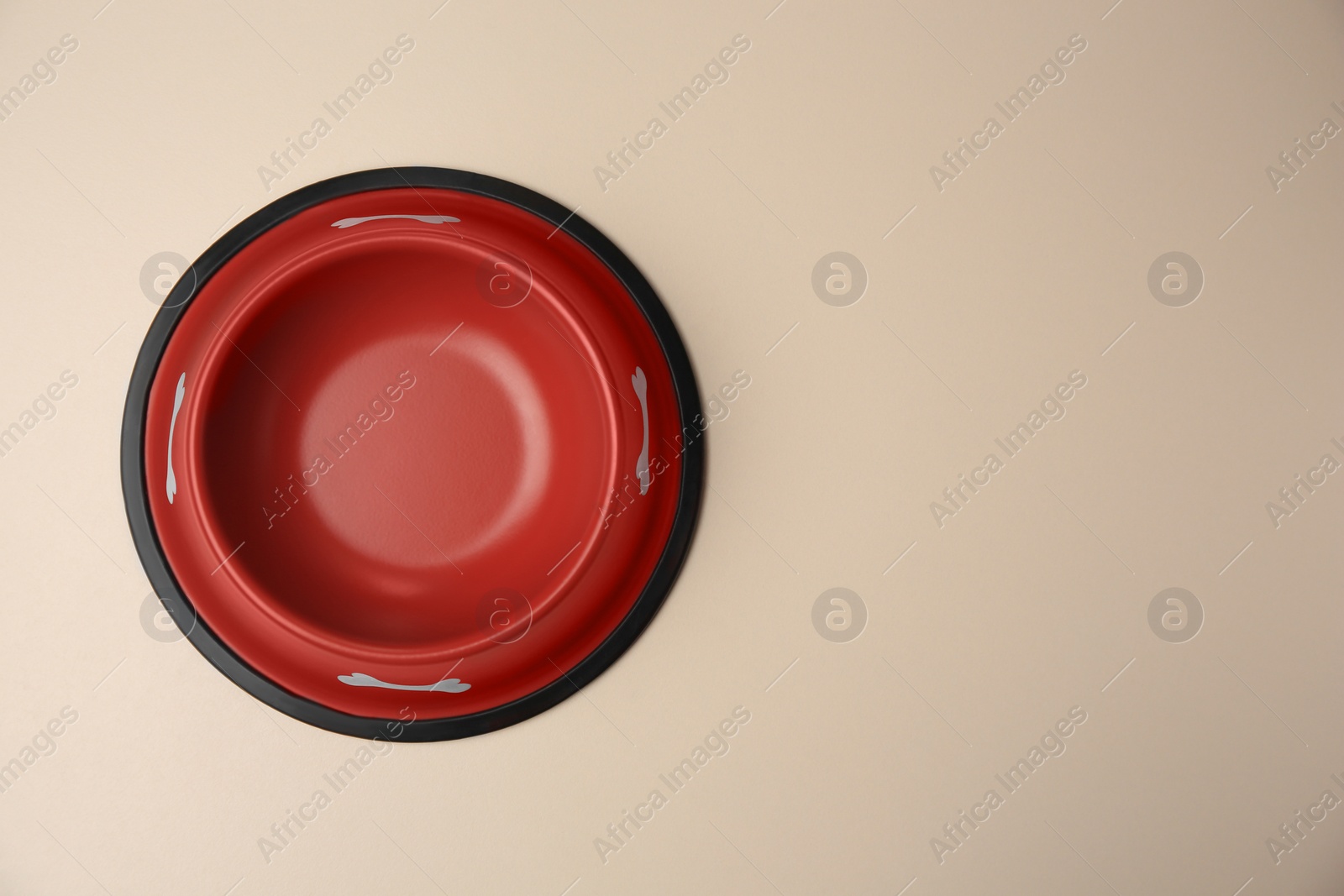 Photo of Empty red feeding bowl on beige background, top view. Space for text