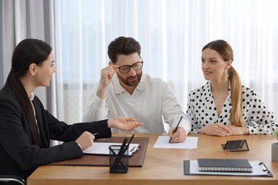 Photo of Couple signing document while having meeting with lawyer in office