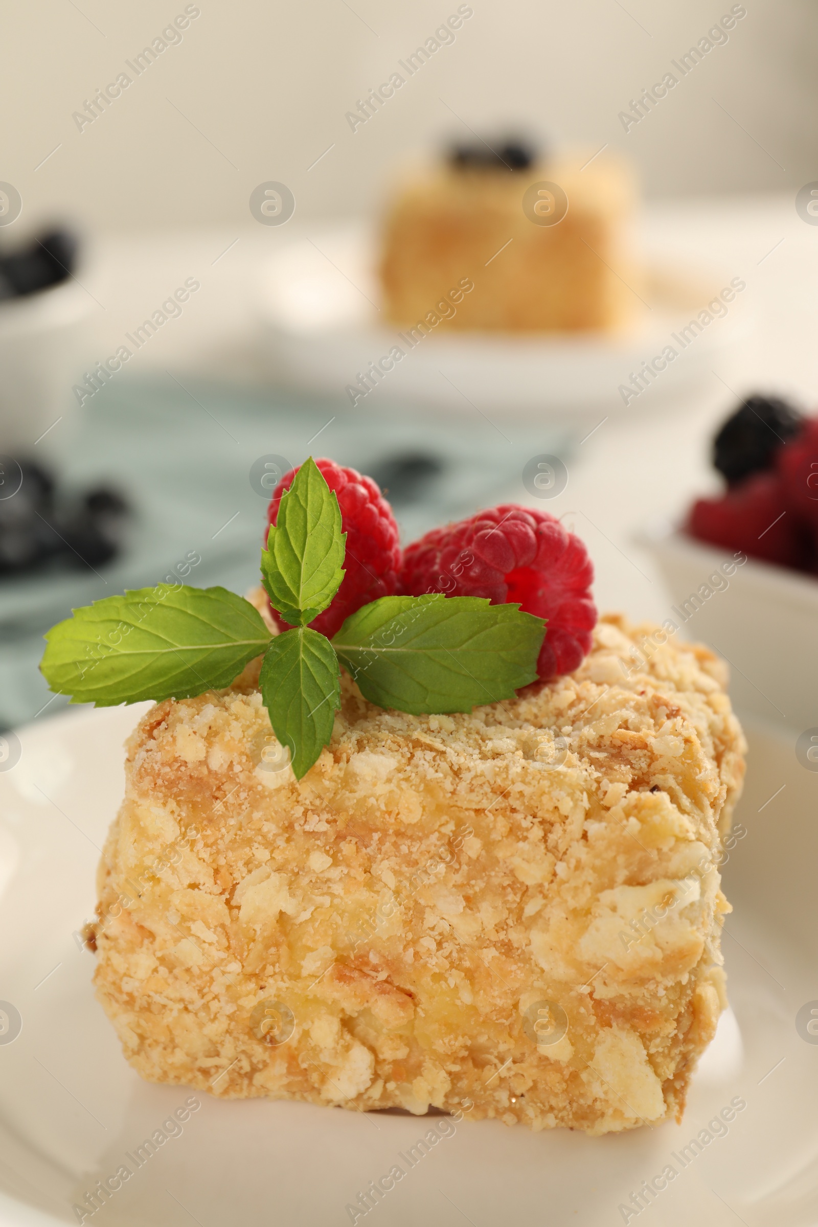 Photo of Piece of Napoleon cake with raspberries on plate, closeup