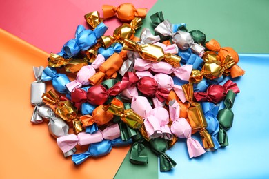 Photo of Many candies in different wrappers on color background, above view