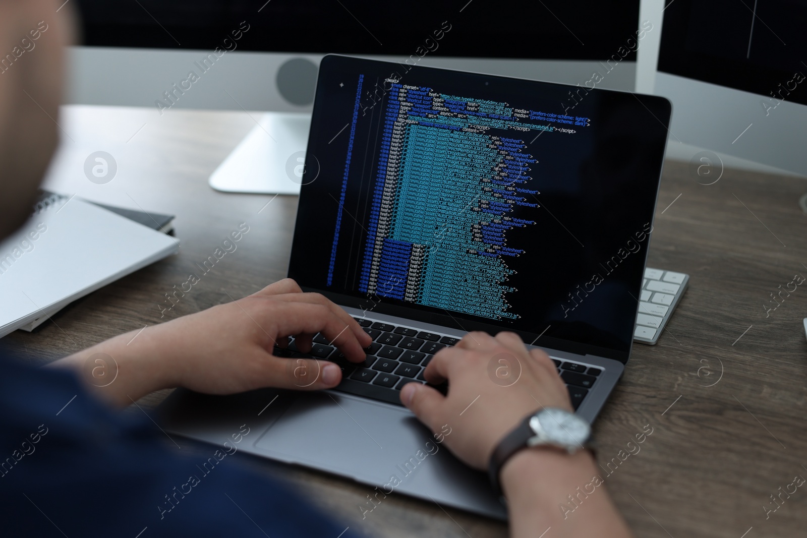 Photo of Programmer working with laptop at desk in office, closeup