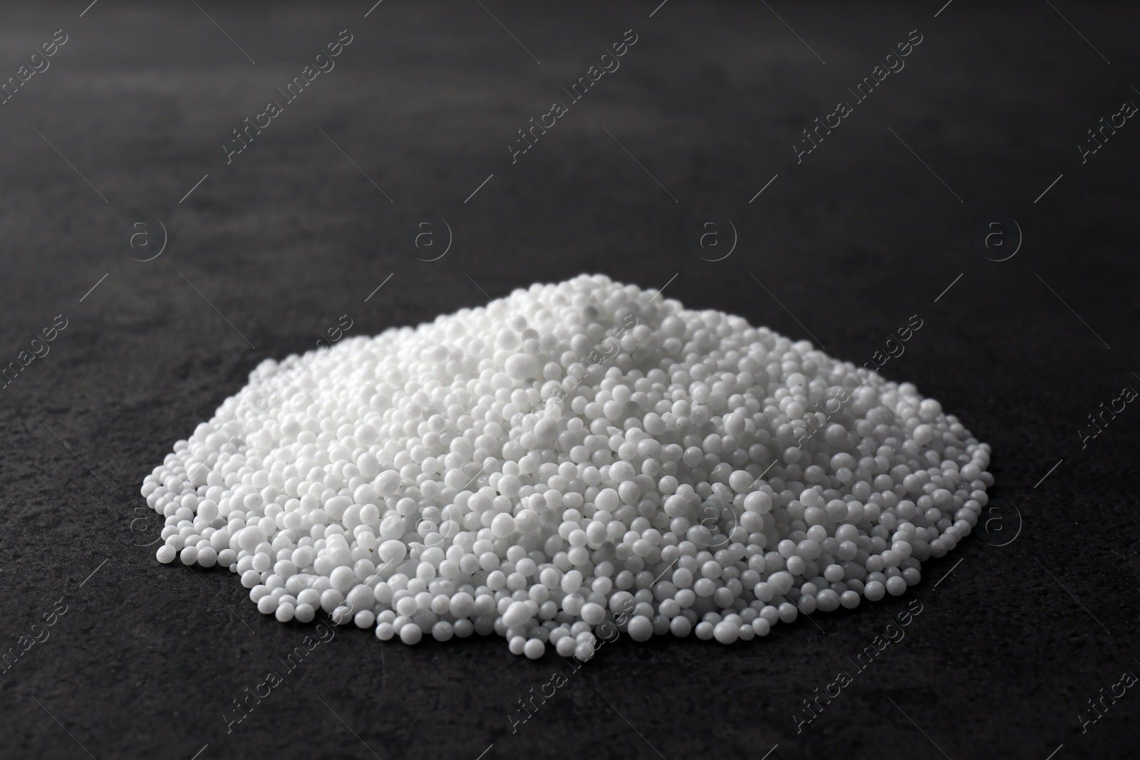 Photo of Pellets of ammonium nitrate on grey table. Mineral fertilizer