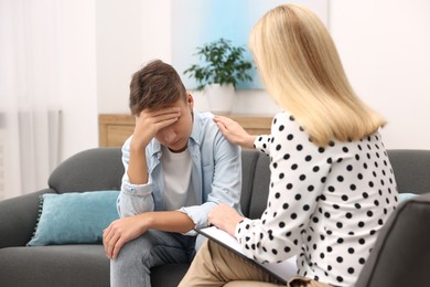 Psychologist working with teenage boy in office