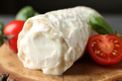 Photo of Delicious fresh goat cheese with tomatoes on wood, closeup