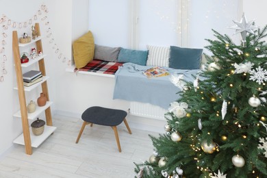 Photo of Beautiful Christmas tree near cozy window sill with pillows and shelf in room, above view. Interior design