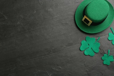 Leprechaun's hat and decorative clover leaves on black background, flat lay with space for text. St. Patrick's day celebration