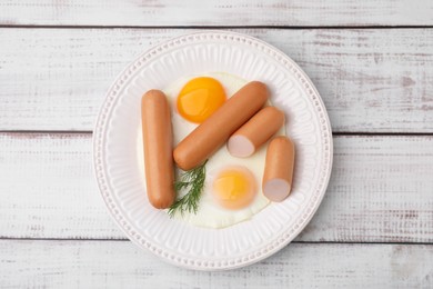 Photo of Delicious boiled sausages, fried eggs and dill on wooden table, top view