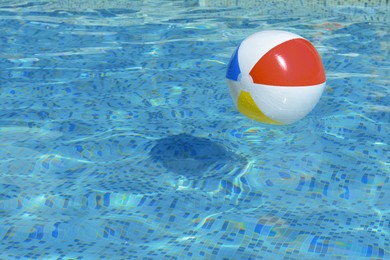 Photo of Inflatable beach ball floating in swimming pool, space for text