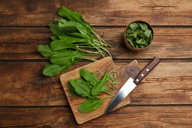 Photo of Fresh green sorrel leaves and knife on wooden table, flat lay