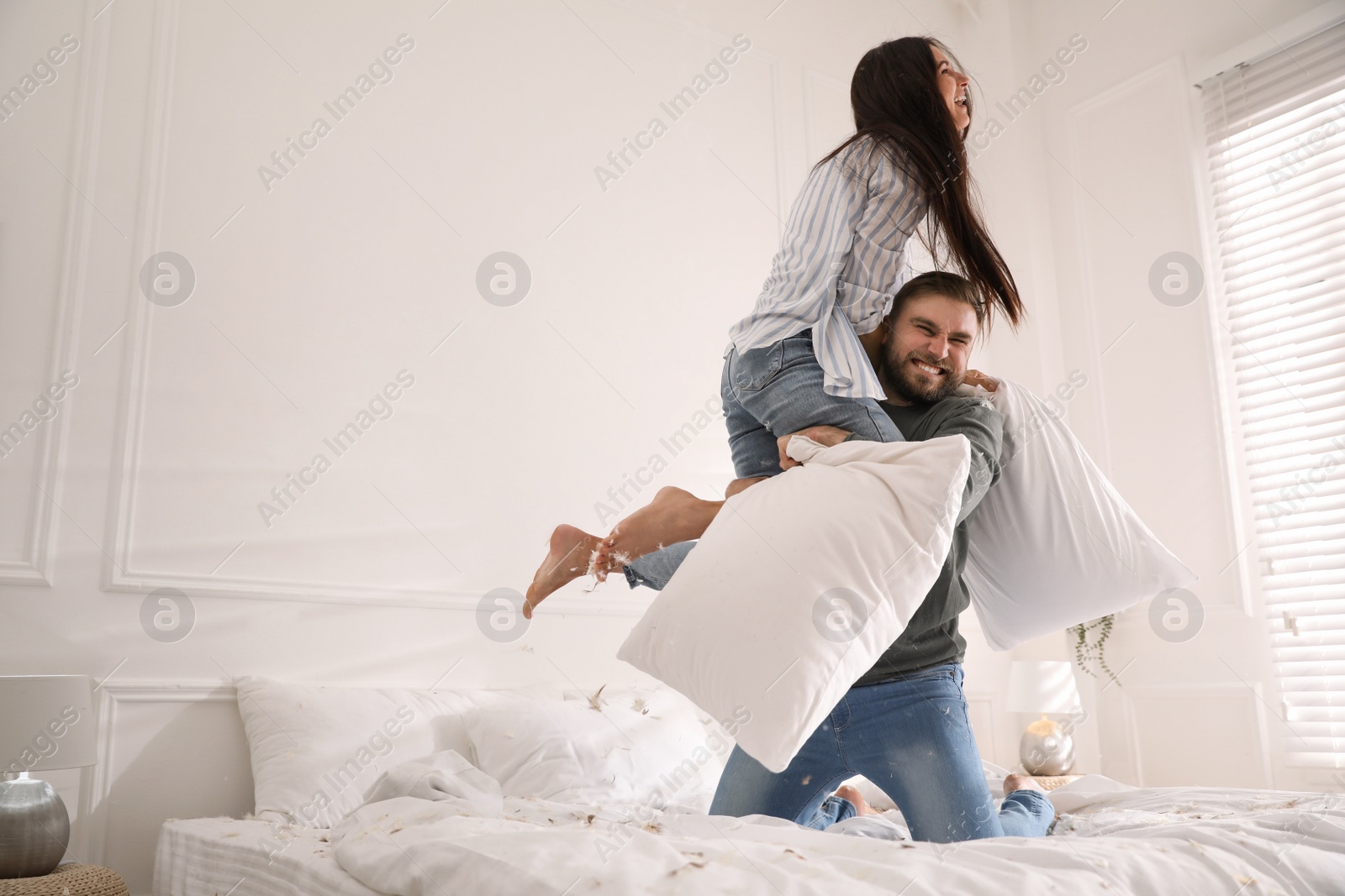 Photo of Happy young couple having fun pillow fight in bedroom