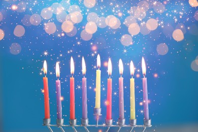 Image of Hanukkah celebration. Menorah with burning candles on blue background with blurred lights, closeup