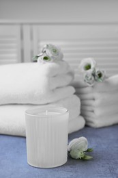 Photo of Scented candle, folded towels and eustoma flowers on gray marble table