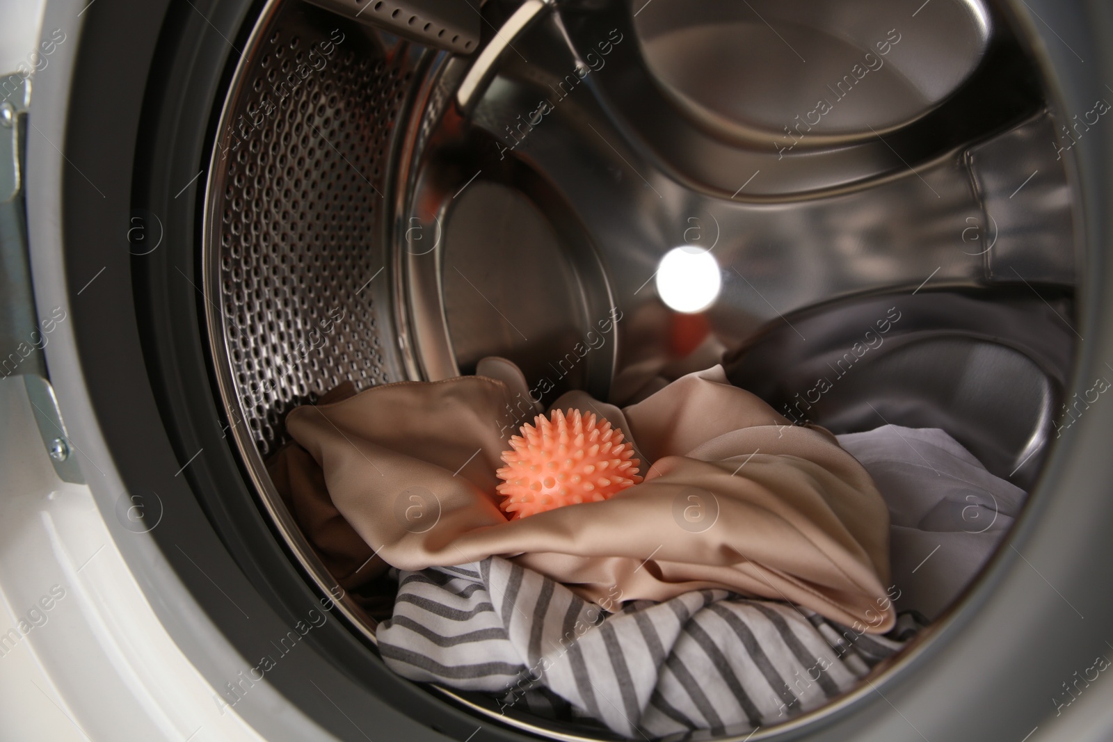 Photo of Dryer ball and clothes in washing machine, closeup