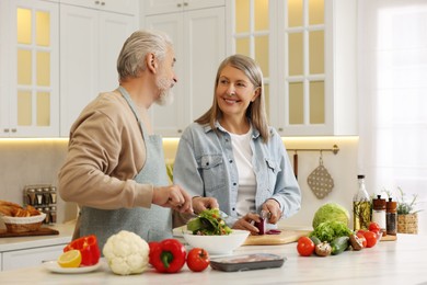 Photo of Happy senior couple cooking together in kitchen