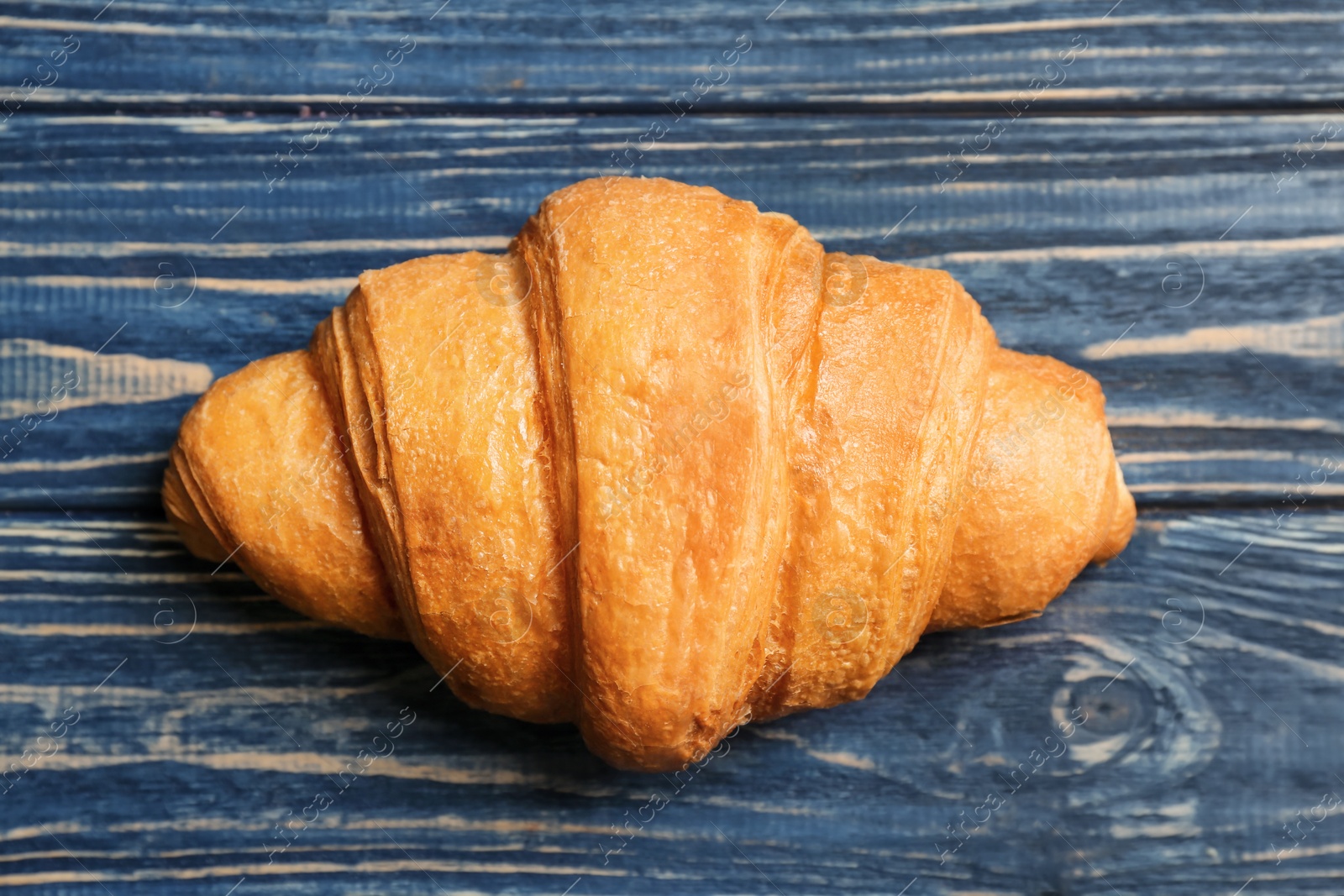 Photo of Tasty croissant on wooden background, top view