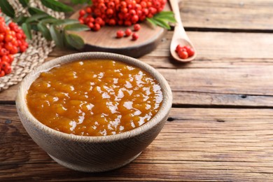 Photo of Delicious rowan jam in bowl on wooden table. Space for text