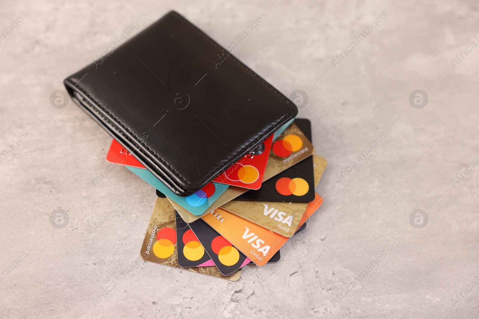 Photo of LEIDEN, NETHERLANDS - MARCH 07, 2024: Bank cards of Visa and Mastercard payment systems in leather wallet on light grey table