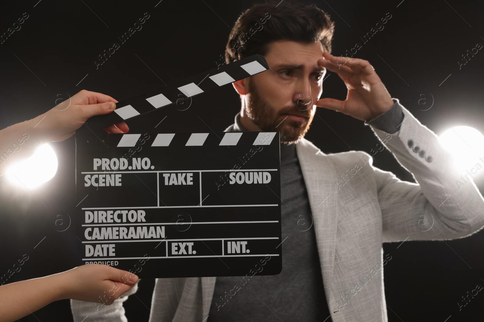 Photo of Actor performing while second assistant camera holding clapperboard on black background, closeup