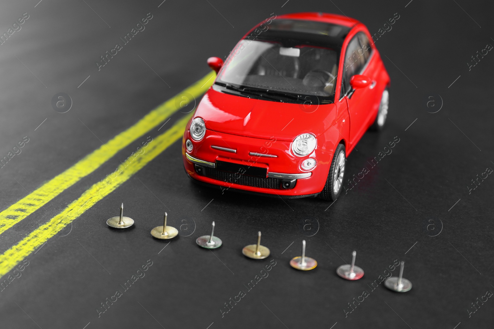 Photo of Pins as barrier blocking way for red toy car. Development through obstacles overcoming