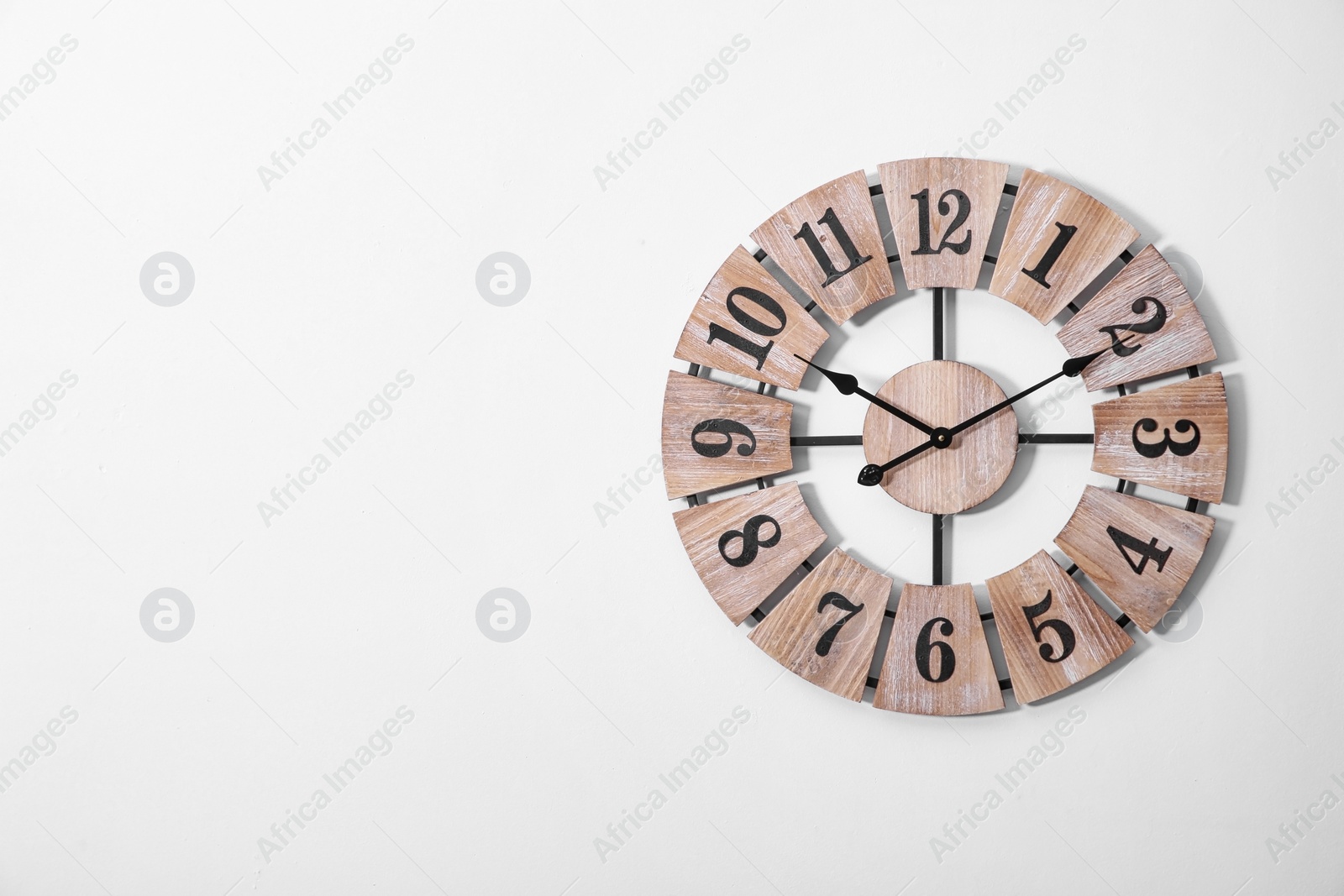Photo of Stylish analog clock on white wall. Space for text