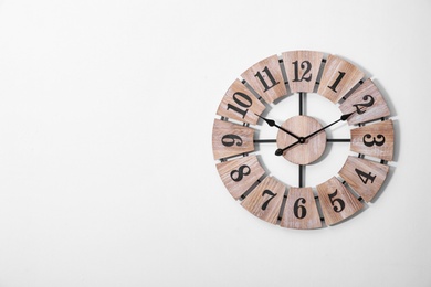 Stylish analog clock on white wall. Space for text