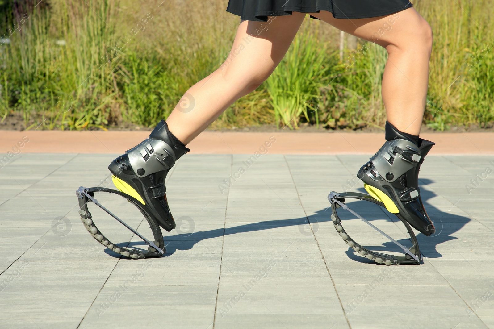 Photo of Woman doing exercises in kangoo jumping boots outdoors, closeup