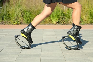 Photo of Woman doing exercises in kangoo jumping boots outdoors, closeup