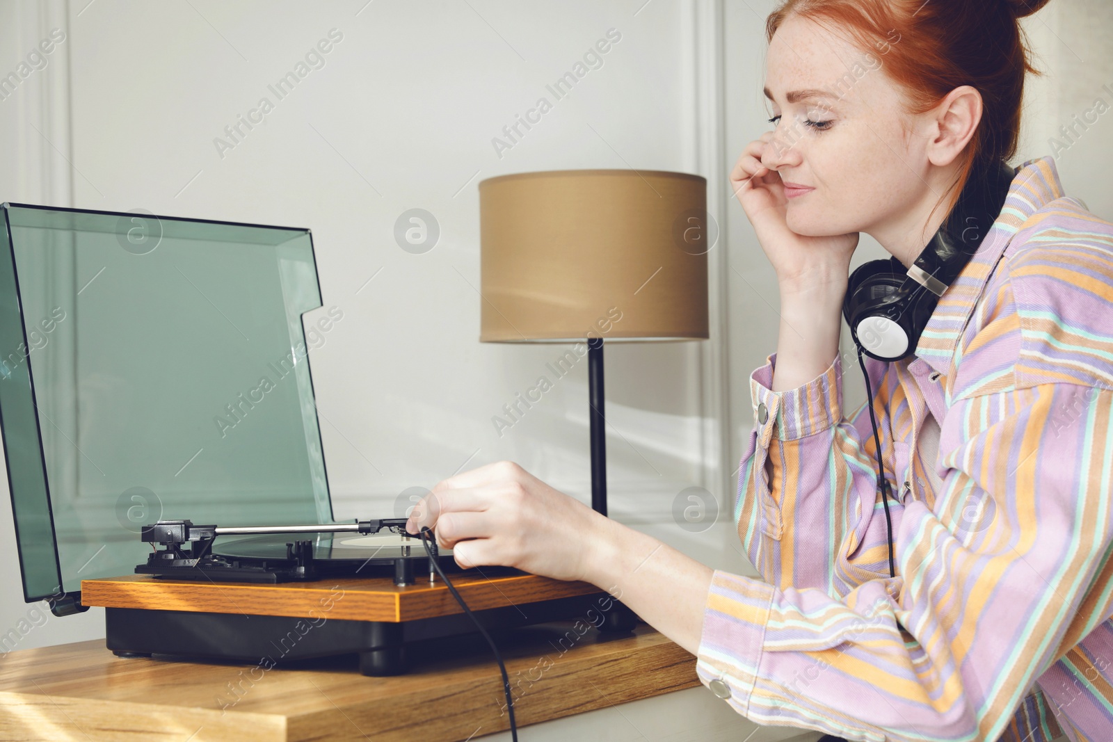 Photo of Beautiful young woman using turntable at home