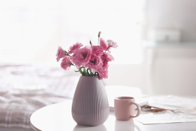 Photo of Vase with beautiful eustoma flowers on table in modern room interior