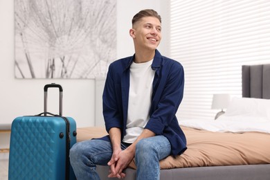 Smiling guest relaxing on bed in stylish hotel room