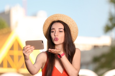 Photo of Happy young woman taking selfie outdoors on sunny day