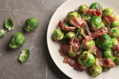 Photo of Delicious Brussels sprouts with bacon on marble table, flat lay