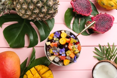 Photo of Flat lay composition with delicious exotic fruit salad  on pink wooden table