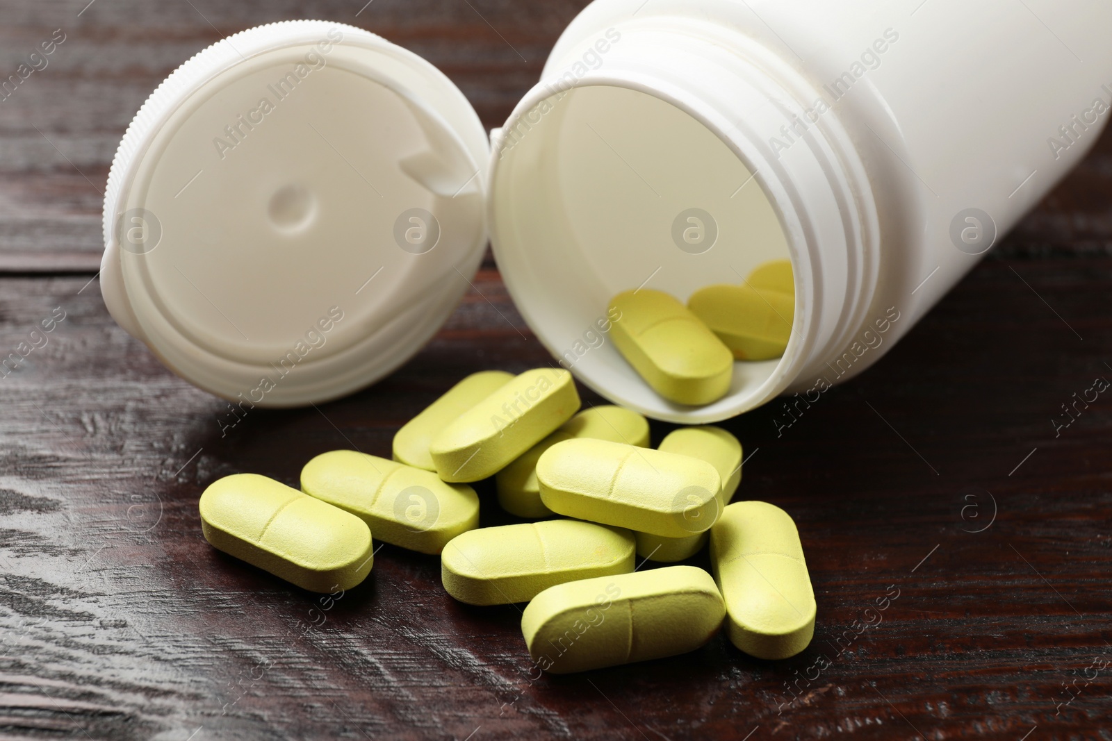 Photo of Bottle and vitamin pills on wooden table, closeup