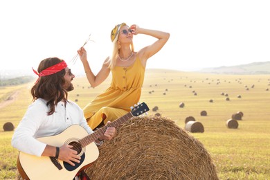 Photo of Beautiful hippie woman listening to her friend playing guitar in field, space for text